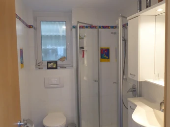 Fewo Strakeljahn Badezimmer Modernes Badezimmer mit blauen Fliesen, Dusche, WC, Handwaschbecken und dekorativen Akzenten.