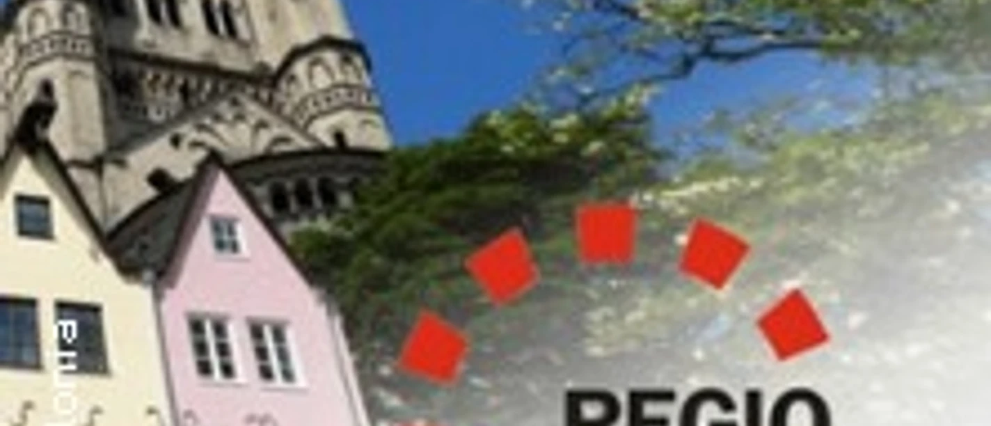Der Kölner Dom und bunte Altstadthäuser steigen majestätisch neben blühenden Bäumen in den Himmel.