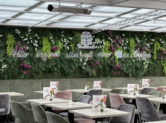 Een lichtovergoten serre met verticale plantendecoraties en zitjes in het café.