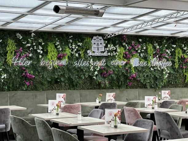 A light-flooded winter garden with vertical plant decorations and seating in the café.