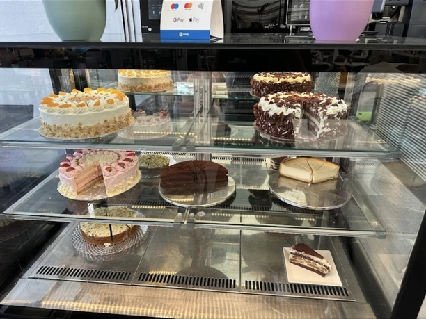 Verschiedene Torten und Kuchen in einer verglasten Vitrine eines Cafés, geschmackvoll präsentiert.