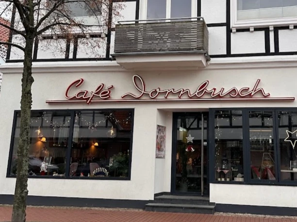 Half-timbered building with Café Dornbusch, wide window front, neon sign and large ice cream cone outside.