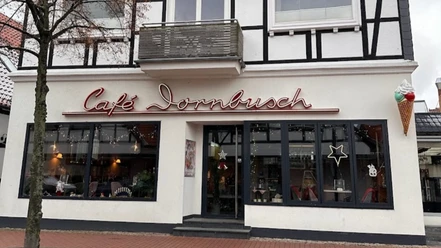 Außenansicht Fachwerkgebäude mit Café Dornbusch, breite Fensterfront, Leuchtreklame und großer Eistüte außen.