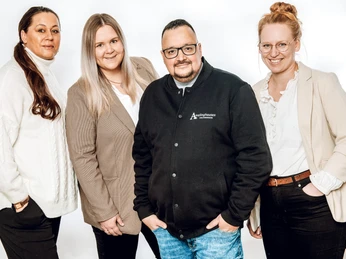 Team-TI-Amelinghausen.jpg Vier freundlich lächelnde Menschen in Business-Kleidung vor weißem Hintergrund.