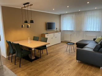 IMG_0551.jpg Moderne, gemütliche Wohnküche mit Holzboden, Esstisch, Stühlen, Ledersofa und TV an der Wand.