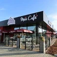 Bäckerei und Café Muss Wessels, Gemeinde Rhauderfehn, Ostfriesland Modernes Café mit schwarzer Fassade und roten Sonnenschirmen, Muss Wessels - Mein Café Schriftzug sichtbar