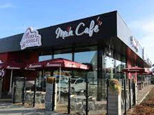 Bäckerei und Café Muss Wessels, Gemeinde Rhauderfehn, Ostfriesland Modernes Café mit schwarzer Fassade und roten Sonnenschirmen, Muss Wessels - Mein Café Schriftzug sichtbar