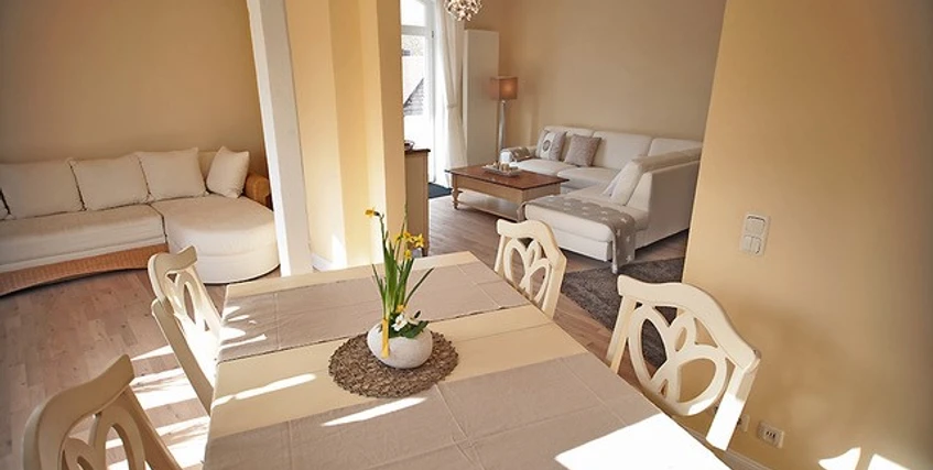 Wohnbereich Heller, offen gestalteter Wohnbereich mit Esstisch, modernen Möbeln und großen Fenstern im Hintergrund.