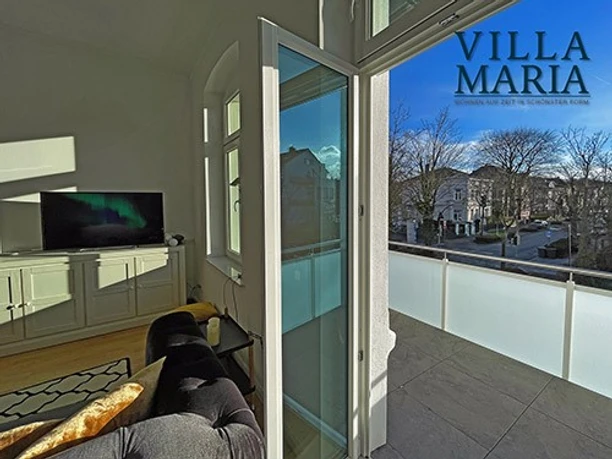 Balkon Blick aus Wohnbereich auf sonnendurchfluteten Balkon mit Aussicht auf ruhige, grüne Parkstraße.