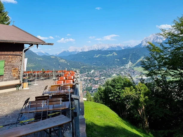 St. Martins Hütte Terrasse einer Berghütte mit leeren Bänken und weitem Blick über Stadt und umliegende Berge