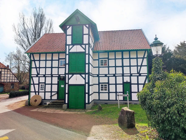 Gutswassermühle Bad Holzhausen Fachwerkgebäude der Gutswassermühle Bad Holzhausen, umgeben von Bäumen und parkendem Auto.