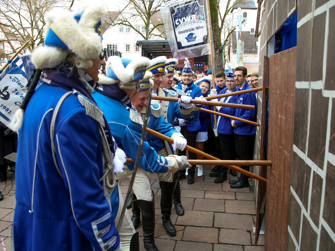 Rosenmontag Bild 5 - Mario Bönning.jpg Teilnehmer in blauen Uniformen amüsieren sich beim symbolischen Sturmbock-Angriff auf eine Holzwand.