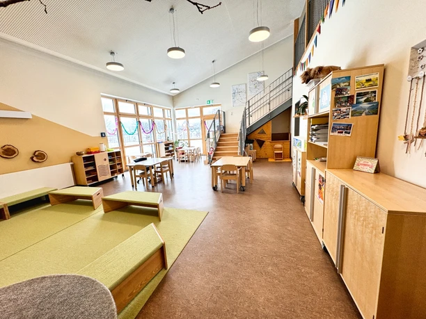 Kindergarten-Amelinghausen (1).jpeg Heller Innenraum im Kindergarten Amelinghausen mit Holztischen und Spielecke.