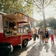 meet & eat Köln Ein farbenfroher Foodtruck auf einem sonnigen Platz, umgeben von Menschen, die in entspannter Atmosphäre Essen genießen.A colorful food truck in a sunny square, surrounded by people enjoying food in a relaxed atmosphere.