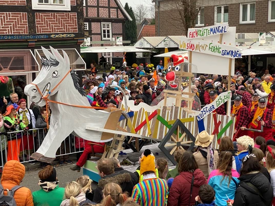 Rosenmontag 2023_7.jpg Karnevalszug mit bunt gekleidetem Publikum, fantasievoller Pferdewagen mit humorvollem Motiv.