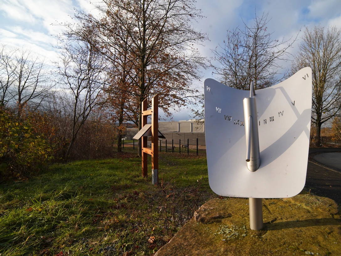 Sonnige Zeiten Sonnenuhr in herbstlicher Parklandschaft mit kahlen Bäumen und bewölktem Himmel fotografiert.