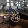 Automuseum Melle Im Automuseum Melle sind historische Autos in einem hellen Raum ausgestellt. Menschen betrachten die Fahrzeuge.