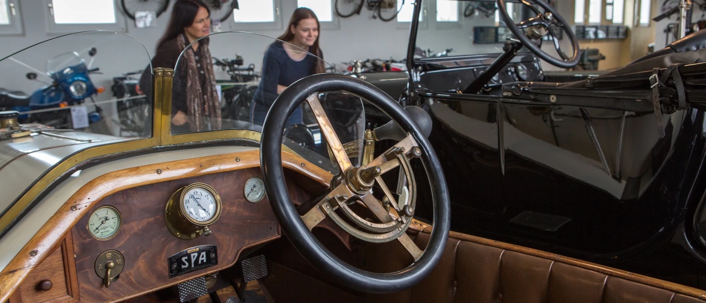 Automuseum Melle Historic cars are exhibited in a bright room at the Melle Automuseum. People look at the vehicles.