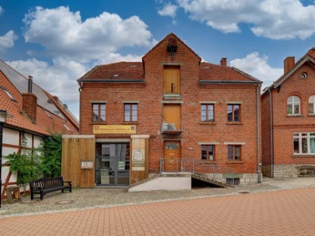 Sackmuseum Backsteingebäude des Sackmuseums mit Rampe, umgeben von gepflasterter Straße und Nachbarhäusern.