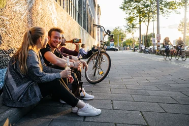 Westwerk Karl-Heine-Straße - Szeneviertel im Leipziger Westen Drei junge Menschen sitzen entspannt mit Getränken in der Hand am Westwerk auf der Karl-Heine-Straße im Leipziger Szeneviertel Plagwitz