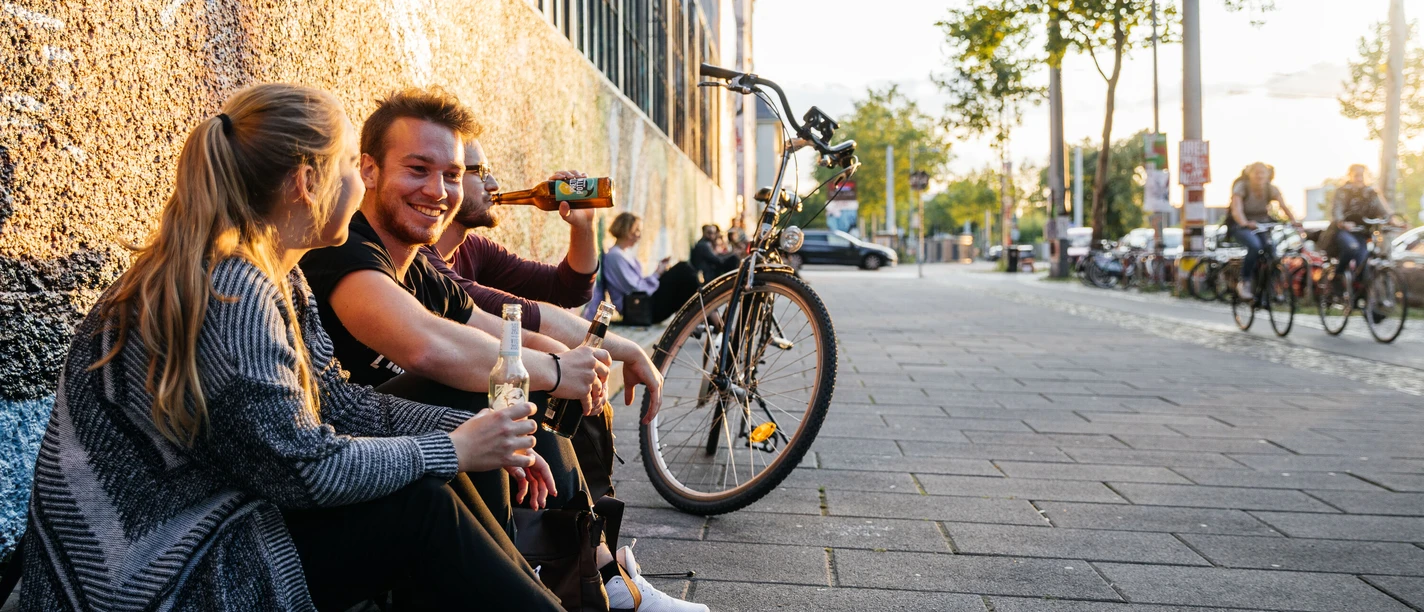 Westwerk Karl-Heine-Straße - Szeneviertel im Leipziger Westen Drei junge Menschen sitzen entspannt mit Getränken in der Hand am Westwerk auf der Karl-Heine-Straße im Leipziger Szeneviertel Plagwitz