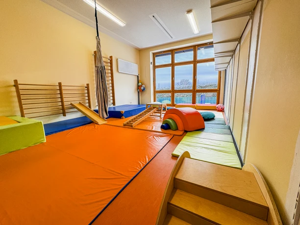 Kinderkrippe-Amelinghausen-21.jpg Bewegungsraum in der Kinderkrippe mit bunten Matten, Hängematte und Turngeräten.
