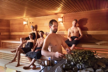 Koppke - Das neue Saunabad in Greetsiel A steam session in the wooden sauna at Koppke Greetsiel, with relaxed guests on the sauna benches