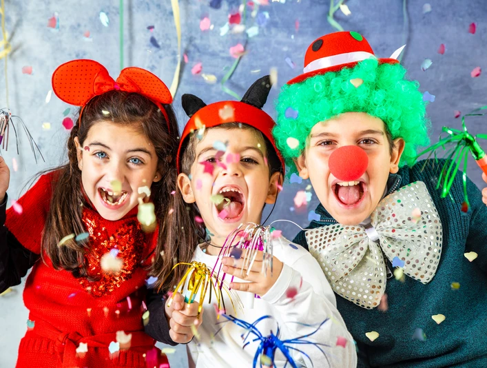 Kinderkarneval in Greetsiel Drei verkleidete Kinder lachen fröhlich, werfen Konfetti und feiern bunt geschmückt den Karneval.