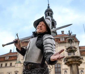 Stadtführung_Ritter Lutz_©-.jpg Einladender Ritter Lutz in Rüstung mit Schwert vor dem historischen Lüneburger Rathaus.