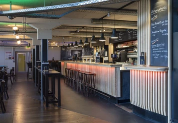 Gastronomiebereich Moderner Gastronomiebereich mit langer Theke, Barhockern und einladendem Ambiente.