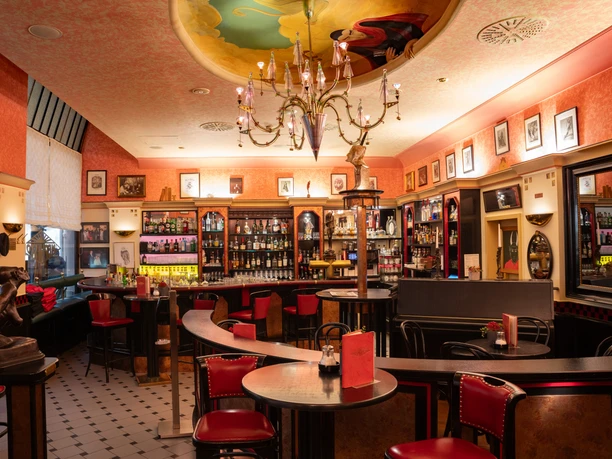 Die großzügige Bar im Mephisto serviert kreative Drinks – Gastronomien in Leipzig Der gemütliche Innenbereich der Mephisto Bar mit vielen roten Sitzmöbeln lädt zum Verweilen ein, Gastronomie