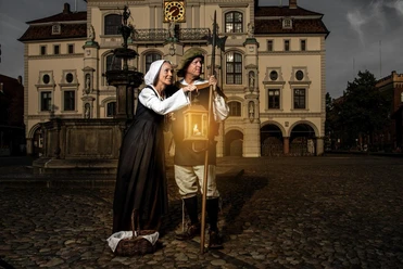 Durch_die_Nacht_mit_Claas_und_Trine.jpg Claas und Trine in historischen Kostümen mit Laterne und Hellebarde vor dem Rathaus Lüneburg.