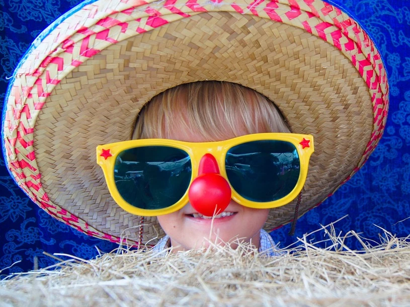 Kinderkarneval.jpg Ein Kind trägt einen Sombrero und große, gelbe Sonnenbrille mit rotem Clownsnasengag im Karneval.