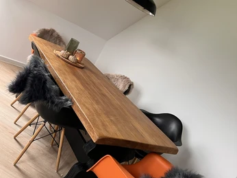 Moderner Essbereich mit großem Holztisch, umgeben von Eames-Stühlen, teils mit Fellkissen.