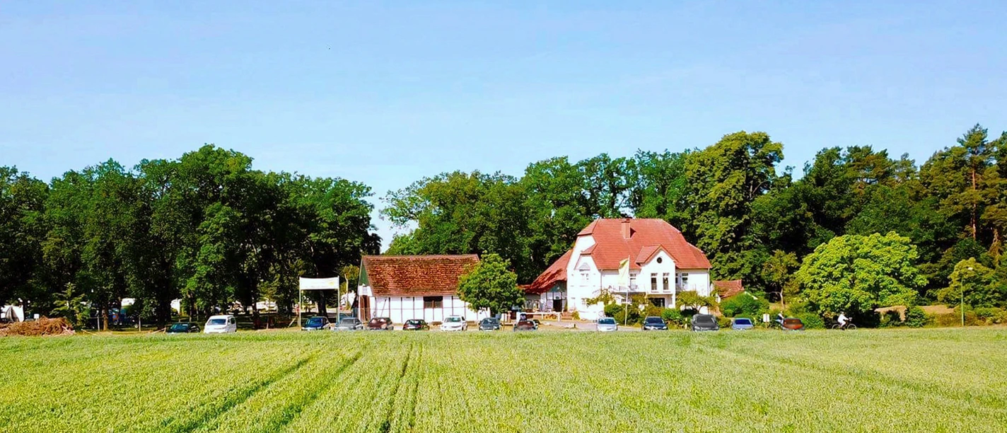 Der Campingplatz liegt am Rand eines weitläufigen Feldes, umgeben von Bäumen und ländlicher Ruhe.