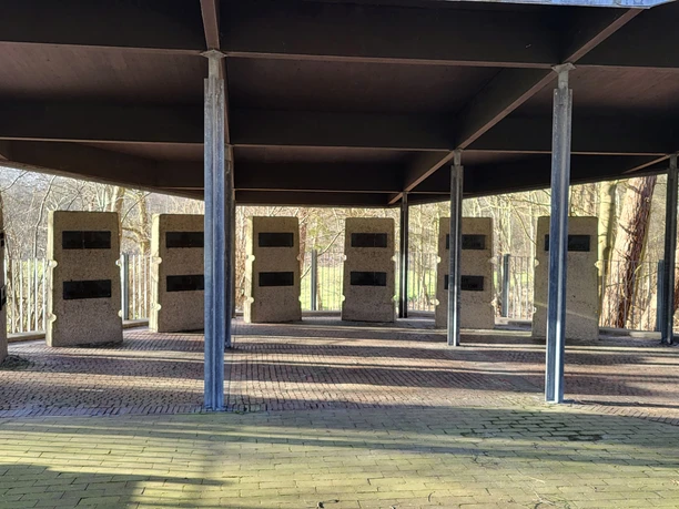KZ Esterwegen Begräbnisstätte, Bockhorst ©Naturpark Hümmling.jpg Überdachte Gedenkanlage mit säulenförmigen Steinwänden und Namensplatten im KZ Esterwegen