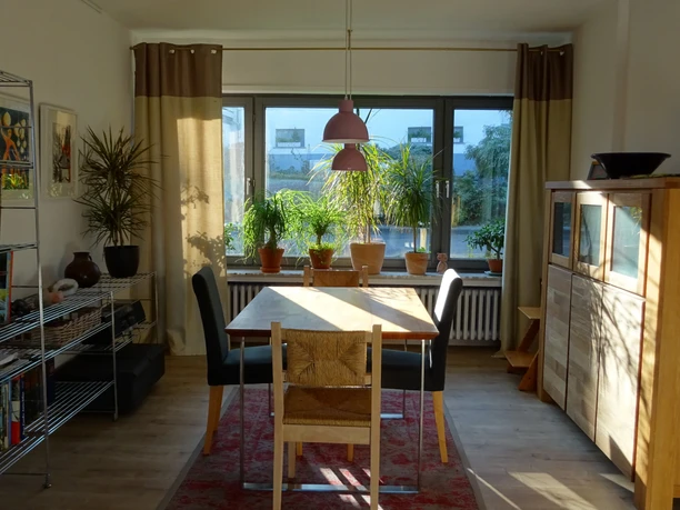 Ferienwohnung Jakobs Essbereich Essbereich mit Holzstühlen und Tisch, Sonnenlicht vom Fenster, Pflanzen auf Fensterbank.