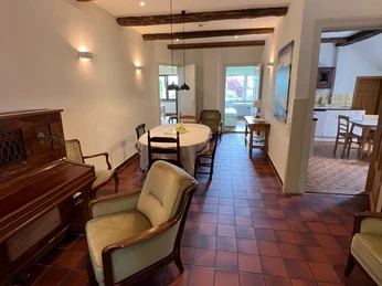 Kochen und Essen in Gretes Hof Diele des Ferienhauses mit roten Steinfußboden, großem Esstisch und Blick in die angrenzende Küche. Entrance hall of the vacation home with red stone floor, large dining table and view into the adjoining kitchen.Feriehusets entré med rødt stengulv, stort spisebord og kig ind i det tilstødende køkken.Inkomhal van het vakantiehuis met rode stenen vloer, grote eettafel en zicht op de aangrenzende keuken.