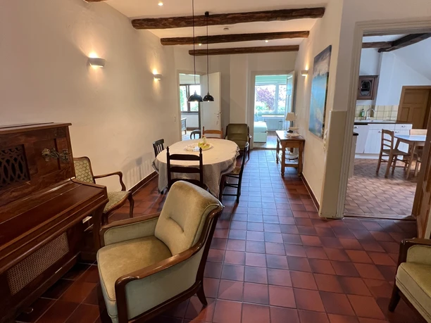 Kochen und Essen in Gretes Hof Entrance hall of the vacation home with red stone floor, large dining table and view into the adjoining kitchen.