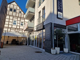Restaurant Bennis Kitchen Delbrück Bennis Kitchen Delbrück: Modernes Restaurant mit Glasfassade, Sonnenschirmen und Fachwerkhaushintergrund.