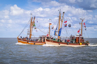 Kutter-Korso-Fahrt Zwei festlich geschmückte Fischkutter fahren nebeneinander über das Meer vor Greetsiel.