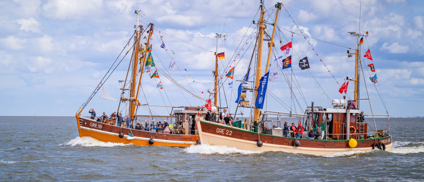 Kutter-Korso-Fahrt Zwei festlich geschmückte Fischkutter fahren nebeneinander über das Meer vor Greetsiel.