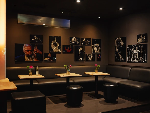 Stadtgarten A cozy, dark room with black leather seating and jazz photographs on the walls.
