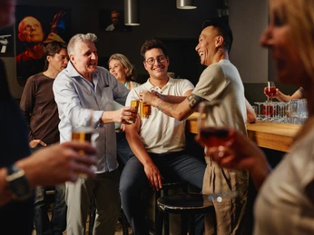 Stadtgarten In einem gemütlichen Barambiente wird ein lebhaftes Gespräch unter Freund*innen geführt.A lively conversation between friends takes place in a cozy bar atmosphere.