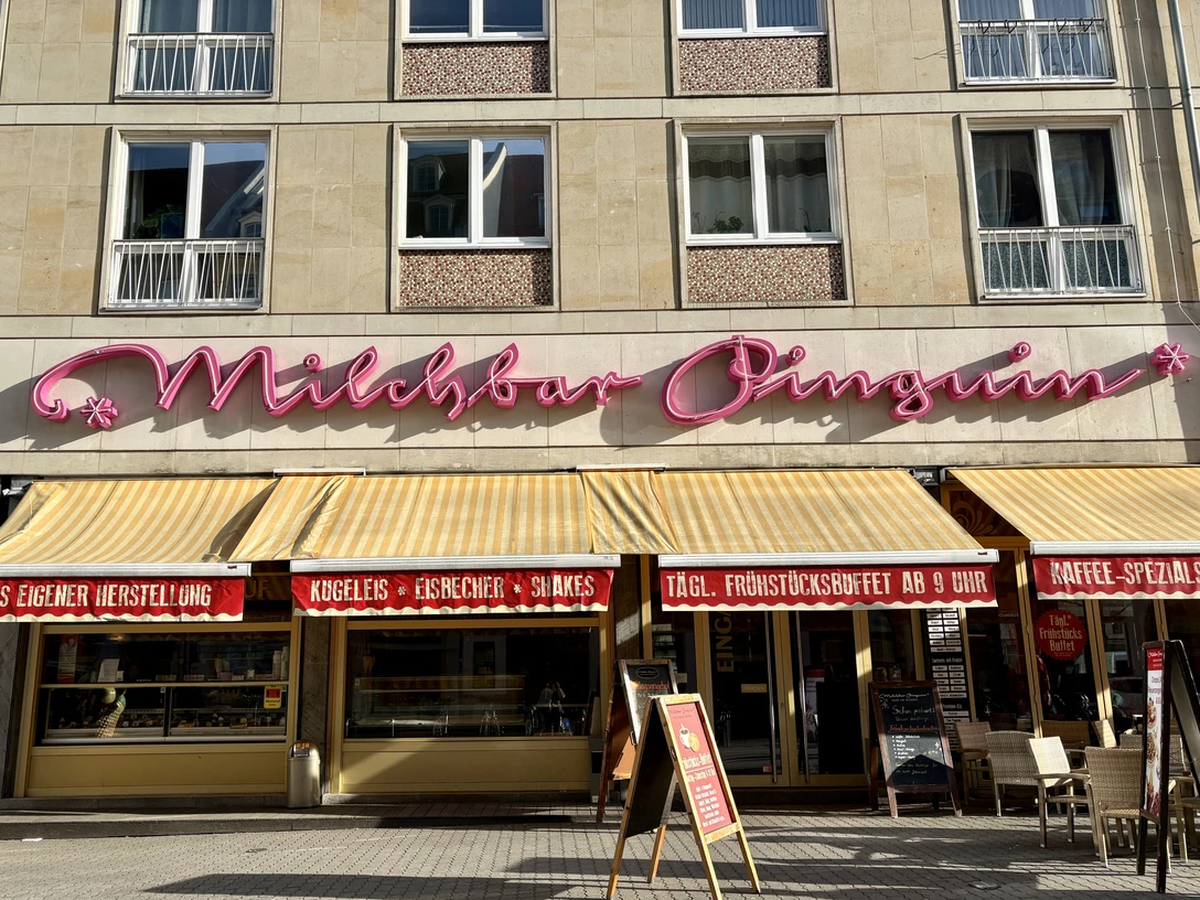 Milchbar Pinguin - Essen mit Kind in Leipzig Der denkmalgeschützte Schriftzug ziert seit den 70er Jahren die Fassade der Milchbar Pinguin.