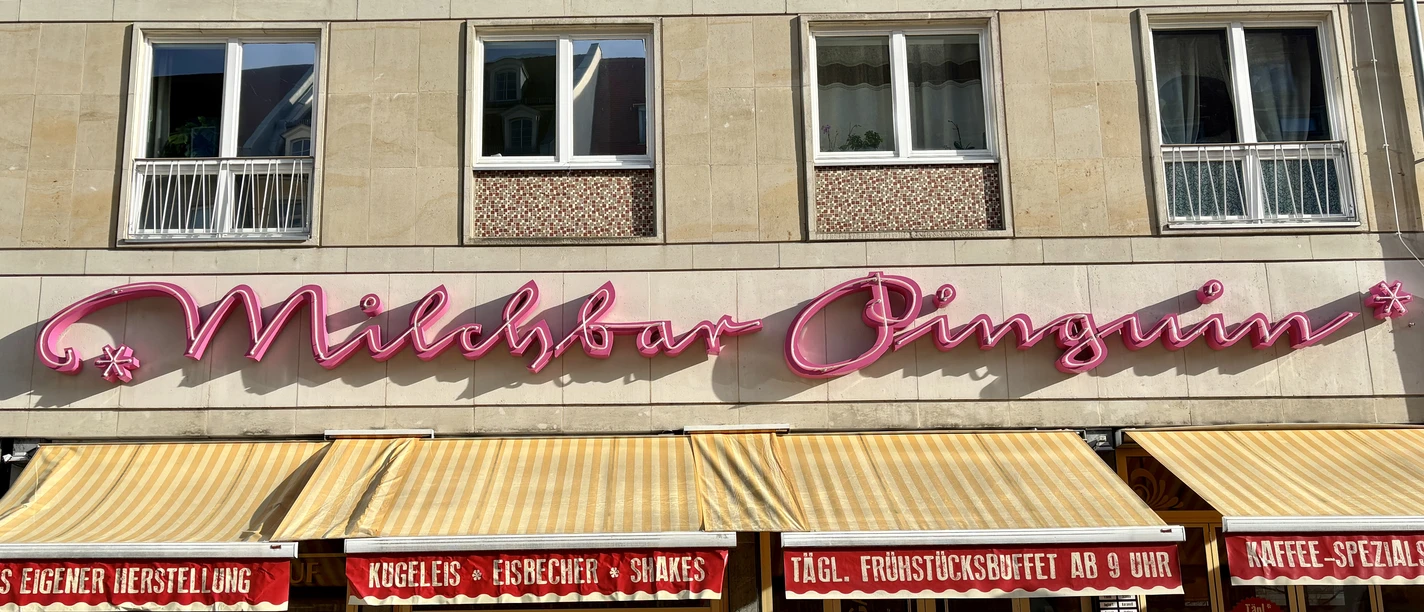 Milchbar Pinguin - Essen mit Kind in Leipzig Der denkmalgeschützte Schriftzug ziert seit den 70er Jahren die Fassade der Milchbar Pinguin.