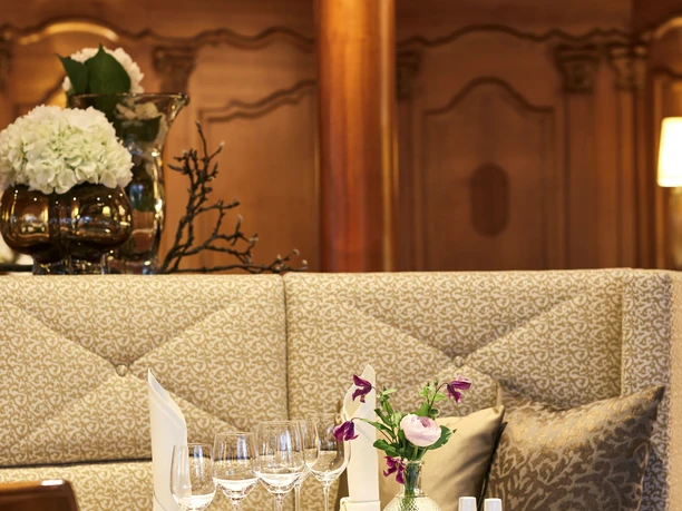 Elegantes Restaurantinterieur mit gedecktem Tisch, Kristallglas, Rosenarrangement und üppigem Kronleuchter.