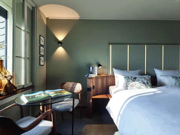 Preferred Plus Room 1-Viveno Group GmbH_L.Thiesbrummel.jpg Gemütliches Zimmer mit Doppelbett, modernem Design, blauen Akzenten und einladendem Naturlicht.