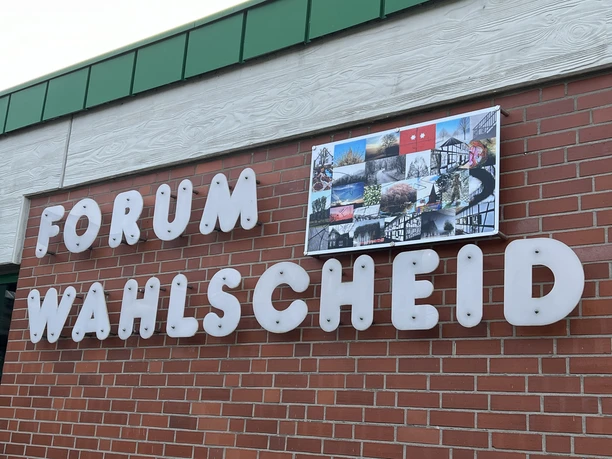 Forum Wahlscheid <p>Backsteinfassade mit der Aufschrift "FORUM WAHLSCHEID" und Fotocollage oberhalb der Buchstaben.</p>