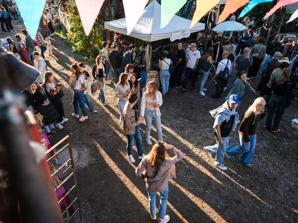Odonien People stroll relaxed in sunny weather at a lively, colorful outdoor market.